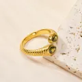 Détail de la bague torsadée dorée avec zircons verts taille poire sur support en pierre - US 7 / Or Pierre Vert Olive