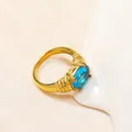 Dettaglio dell'anello retrò in titanio dorato con trama a coste e zircone blu ovale - Oro Gemma Blu Acqua