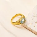 Dettaglio anello dorato vintage con gemma blu ovale e fascia con trama a rilievo - Oro Blu Chiaro Zirconia