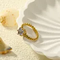 Detail van 18k vergulde titanium ring met kroongezette zirkoon op een schelpdisplay - US 6 / Goud Wit Zirconia