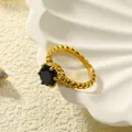 Macro-opname van een 18k vergulde ring met zwarte edelsteen op een schelp en zand - Goud Zwart Zirconia