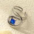 Makroaufnahme: Silberring mit blauem Zirkon auf mehrlagigem, geschwungenem Band - Einstellbar Offen / Edelstahl Silberfarbe Blauer Zirkonia