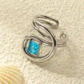 Makroaufnahme des geschwungenen Silberrings mit quadratischem blauem Stein auf Stein - Einstellbar Offen / Stahlfarbe mit seeblauem Zirkonia