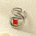 Detail eines quadratischen roten Zirkonias auf einem silbernen offenen Edelstahlring - Einstellbar Offen / Stahlfarbe Orangeroter Strass