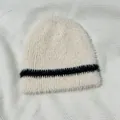 Detailansicht der weichen beigen Strickmütze aus Webpelz mit schwarzen Kontraststreifen - 22x20cm / Aprikose