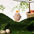Detail van een pluche paaskuiken hanger in een feestelijke groene mos decoratie - Koffie Kuiken