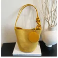 Detail of yellow suede bucket bag featuring woven knot shoulder strap and mini coin purse - Yellow