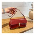 Borsa a spalla retrò in pelle verniciata rossa con fibbia dorata su piano in legno - Rosso
