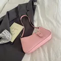 Elegante bolso de hombro rosa claro con hebilla plateada sobre fondo de tela blanca pura - Rosa