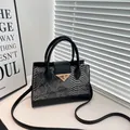 Chique crossbodytas met zwart-grijze slangenprint en gouden driehoekige sluiting - Zwart
