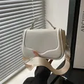 White minimalist crossbody bag with wavy flap design and wide fabric strap in cream - White