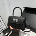 Elegant black glitter handbag with silver metal bow and shiny leather flap detail - Black