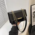Elegant black patent leather crossbody bag with a gold rectangular buckle and chain strap - Black