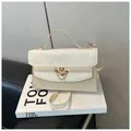 Sac bandoulière chic blanc cassé avec ferrures dorées et détails de chaîne sur un livre - Beige