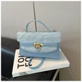 Sac à bandoulière bleu clair avec rabat plissé en cuir et fermoir doré sur un livre - Bleu