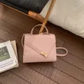 Sac bandoulière rose à texture ondulée et boucle dorée sur un sol en bois - Rose Sans Pendentif