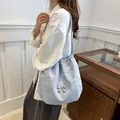 Light blue drawstring bucket bag with silver bow accent and slim shoulder strap - Blue