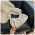 Detalle del bolso nube blanco mostrando el cuero sintético brillante y asa con pliegues - Blanco