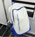 Detalle de mochila azul y beige con letras impresas y colgante de rana gris en carro - Mochila azul real sin colgante