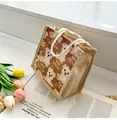 Nahaufnahme der Leinen-Bärentasche mit Baumwollseilgriff und floralem Kunsthintergrund - Braun