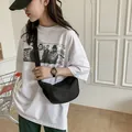 Sac bandoulière demi-lune minimaliste en nylon noir porté avec un style décontracté - Noir