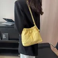 Bright yellow quilted rhombic shoulder bag with gold chain and ball charm shown on model - Yellow