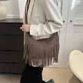 Brown suede hobo bag with tassel fringe detail worn over a white blazer - Coffee