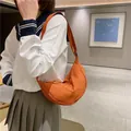 Sac hobo croissant en nylon orange vif avec bandoulière réglable porté par un mannequin - Rouge Orangé