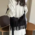 Minimalist black suede shoulder bag with long fringe and zip closure shown on a model - Black