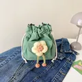 Mini light green canvas drawstring bucket bag with floral decor on denim background - Green