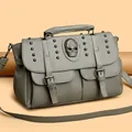 Graue Punk-Handtasche aus Kunstleder mit silbernem Totenkopf und Nieten in Seitenansicht - Grau