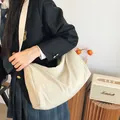 Minimalistische beige Nylon-Umhängetasche mit Falten-Design getragen von einem Modell - Weiß