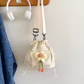 Cream canvas drawstring bucket bag with floral detail and cherry charm on wooden hook - White