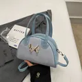 Light blue bowling style crossbody bag with metallic butterfly buckle and suede texture - Blue without Pendant