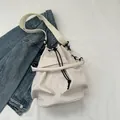 Minimalistische beige Kordelzug-Beuteltasche mit schwarzen Beschlägen und Schultergurt - Weiß