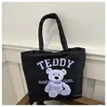 Black quilted tote bag with purple teddy bear print and double handles for daily use - White