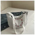 White corduroy tote bag featuring a red circular letter print and adjustable shoulder strap - White