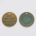 Macro view of vintage bronze pendants with She believed she could so she did engraving - Antique Green