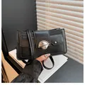 Minimalist black matte crossbody bag with circular silver metal buckle and slim strap - Black