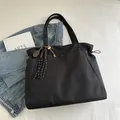 Large black commuter tote bag with gold tennis racket charm and woven tassel detail - With Pendant / Black