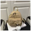 Beige corduroy mini backpack with black smiley face patterns and a white pompom charm - Khaki