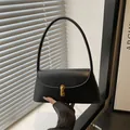 Bolso baguette negro minimalista con cierre cilíndrico dorado y correa delgada elegante - Negro