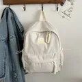Beige minimalist backpack with yellow smiley face patch and drawstring side pockets - White