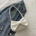 Bolso de hombro blanco estilo Y2K con lazo grande sobre fondo de mezclilla azul - Blanco