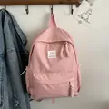 Minimalist pink backpack for students featuring a white smiley badge and fashion lettering - Pink