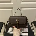 Dunkelbraune Handtasche aus Leder mit Litschimuster, Hufeisenschnalle und Umhängeriemen - Braun