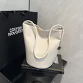 Minimalist beige pebble leather bucket bag with silver chain and metal pendant detail - White