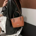 Eimerbeutel aus karamellfarbenem Leder mit Litschi-Struktur und Fashion-Logo aus Silber - Braun
