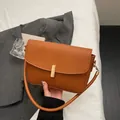 Bolso bandolera rectangular marrón caramelo con hebilla dorada en un entorno minimalista - Marrón