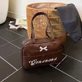 Brown patent leather handbag with white bow accent and Gonand embroidery details - Coffee
